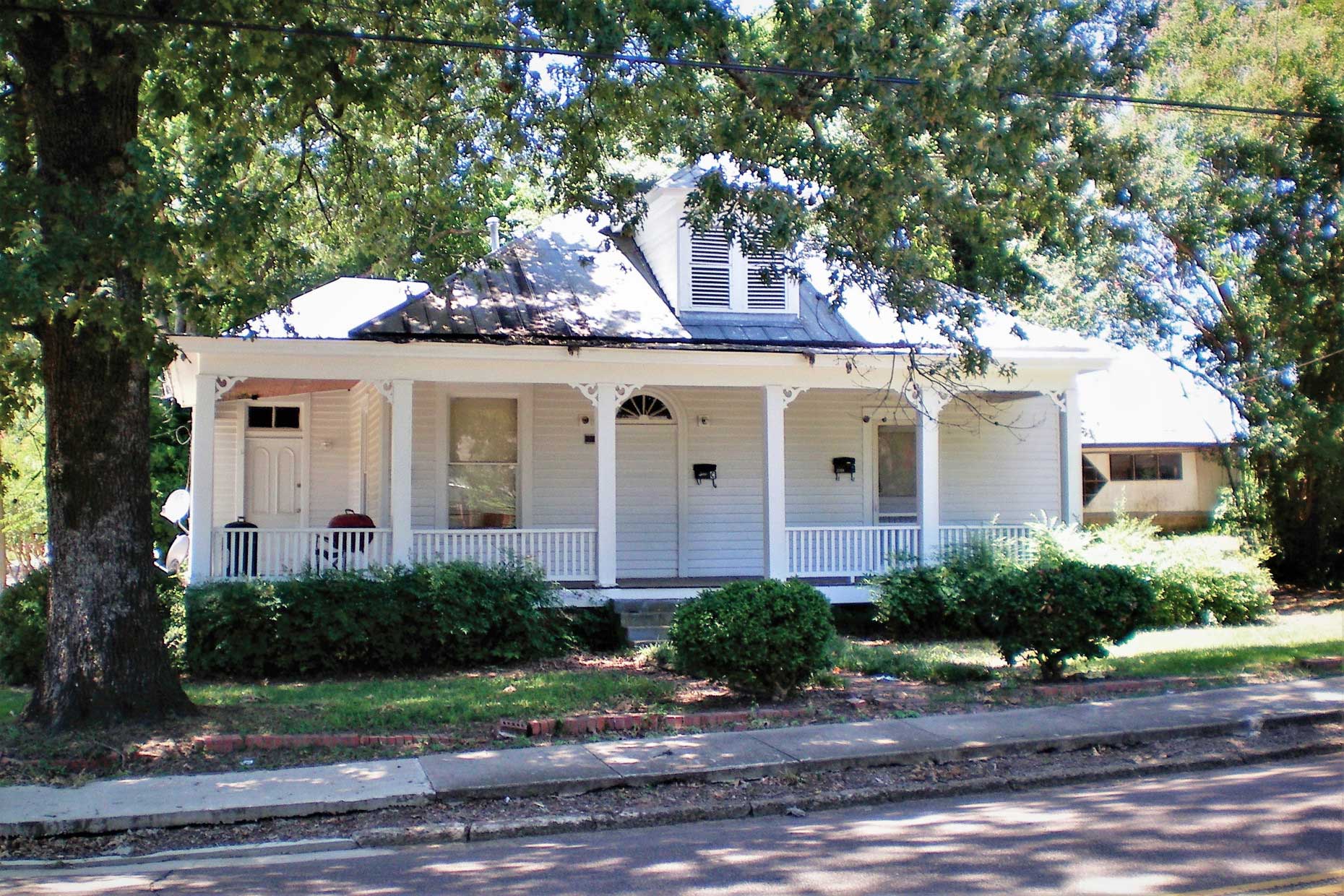 old home on street under large trees